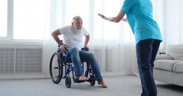 Enfermera animando a vieja paciente discapacitada a salir de la silla de ruedas — Vídeo de stock