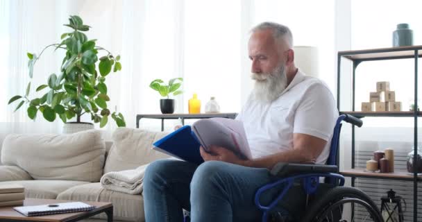 Homme handicapé assis en fauteuil roulant et écrit dans des documents déposés — Video