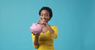 Kadın domuz kumbarasına para sokuyor.