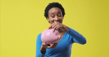 Kadın domuz kumbarasına para sokuyor.