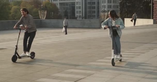 Радісна пара їде на електричному скутері в місті — стокове відео