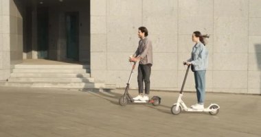 Şehirde elektrikli scooter kullanan bir çift.