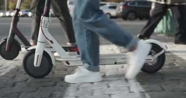 Şehir caddesinde e-scooterlı bir çift yürüyor.