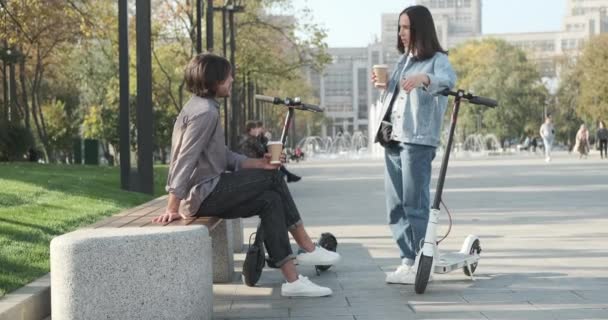 Par taler med kaffekop og e scooter i parken – Stock-video