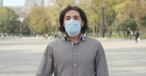 Mężczyzna w masce ochronnej dotykający klatki piersiowej pięścią — Wideo stockowe