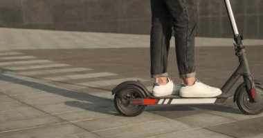 Şehirde elektrikli scooter kullanan bir adam.