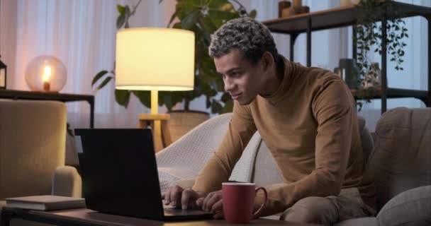 Mannen som använder laptop sitter på soffan på natten — Stockvideo