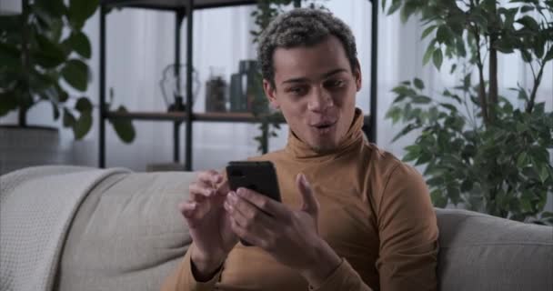 Evde cep telefonu kullanan heyecanlı bir adam — Stok video