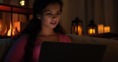 Gece geç saatlerde evde dizüstü bilgisayar kullanan bir kadın.