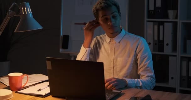 Affärsman lyssnar musik på airpods medan du arbetar sent på kvällen på kontoret bärbar dator — Stockvideo