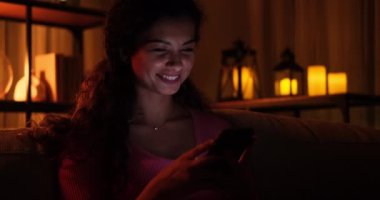 Gece geç saatlerde evde cep telefonu kullanan bir kadın.