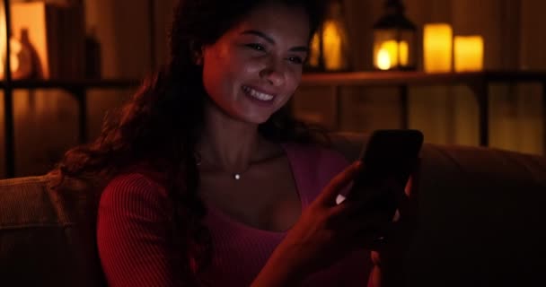 Vrouw chatten met behulp van mobiele telefoon 's avonds laat thuis — Stockvideo