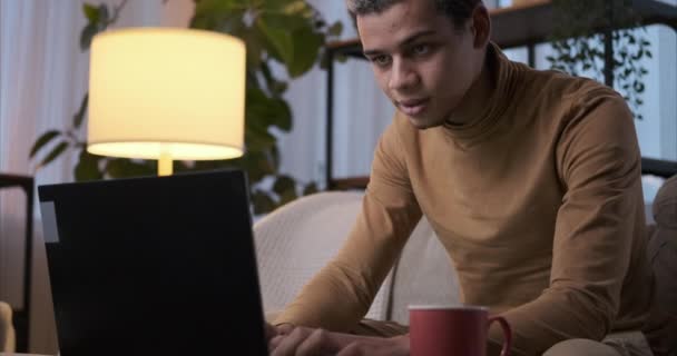 Mann benutzt Laptop und trinkt Kaffee zu Hause — Stockvideo