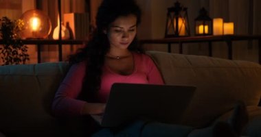 Gece geç saatlerde evde dizüstü bilgisayar kullanan bir kadın.