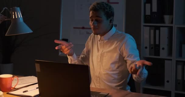 Geschäftsmann hört Musik auf Airpods, während er spät in der Nacht am Büro-Laptop arbeitet — Stockvideo