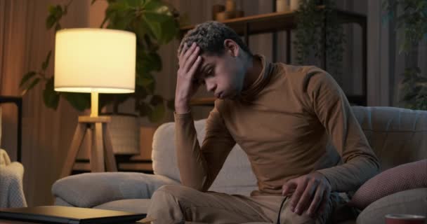 Muž trpící depresí sedí v noci na gauči — Stock video