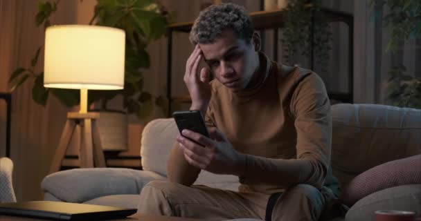 Depressieve man gefrustreerd proberen om zichzelf te vermaken met behulp van mobiele telefoon — Stockvideo