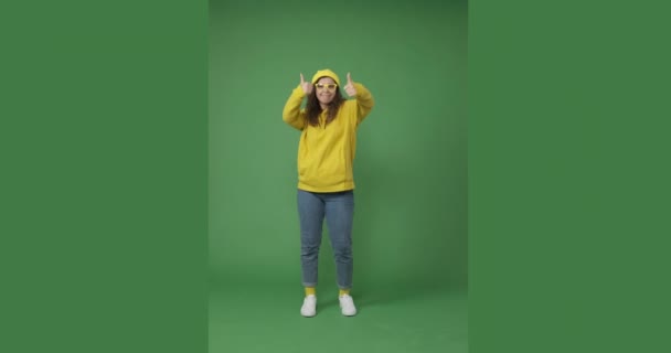 Mujer dando pulgares hacia arriba gesto y bailando sobre fondo verde — Vídeos de Stock