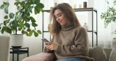 Evde cep telefonu kullanan bir kadın.