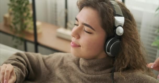 Vrouw die thuis muziek luistert op een koptelefoon — Stockvideo