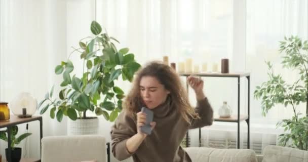 Женщина поет, используя мобильный телефон в качестве микрофона — стоковое видео