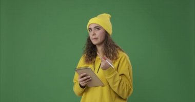 Yeşil arka planda not defterine yazan kadın