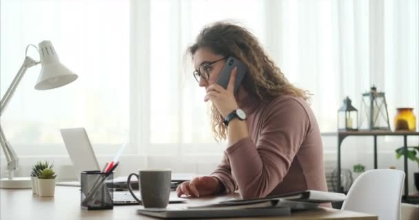 Жінка використовує мобільний телефон і ноутбук під час роботи в офісі — стокове відео