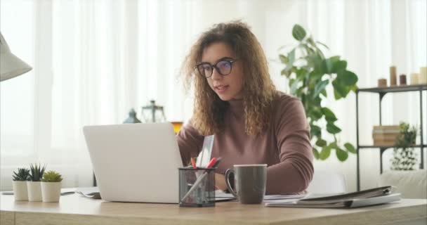 Mujer analizando documentos y trabajando en laptop — Vídeo de stock