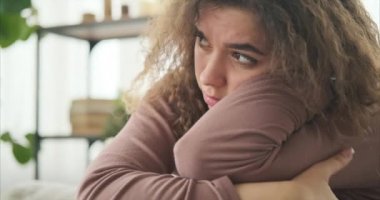 Üzgün yüzüyle evde oturan bir kadın.