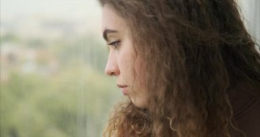 Üzgün kadın parmaklarıyla pencereye çiziyor.