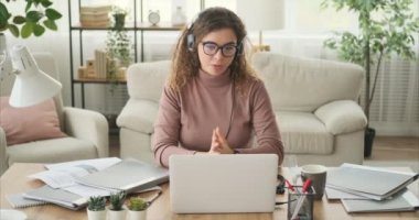 İş kadını bilgisayar ve kulaklık kullanarak video görüşmesi yapıyor.