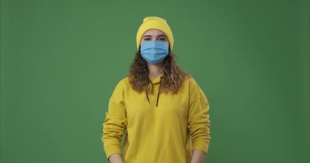 Γυναίκα φορώντας προστατευτική μάσκα προσώπου και δίνοντας διάφορες χειρονομίες χαιρετισμού πάνω από την πράσινη οθόνη — Αρχείο Βίντεο