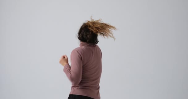 Возбужденная женщина танцует на белом фоне — стоковое видео