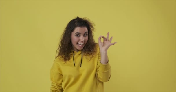 Frau gibt ok Handzeichen und Liebesgeste über gelbem Hintergrund — Stockvideo