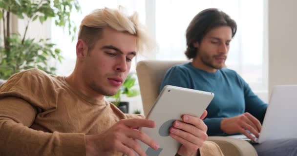 Coppia gay che utilizza tablet e laptop digitali a casa — Video Stock