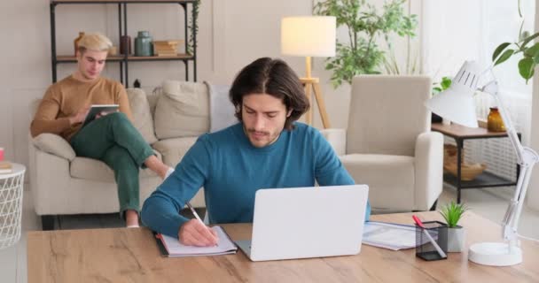 Uomo che lavora sul computer portatile mentre il suo ragazzo sta usando tablet digitale sul divano di casa — Video Stock