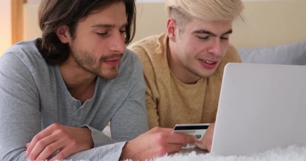 Pareja gay celebrando usando laptop y tarjeta de crédito en la cama — Vídeos de Stock