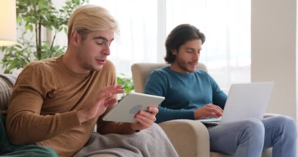 Coppia gay che utilizza tablet e laptop digitali a casa — Video Stock