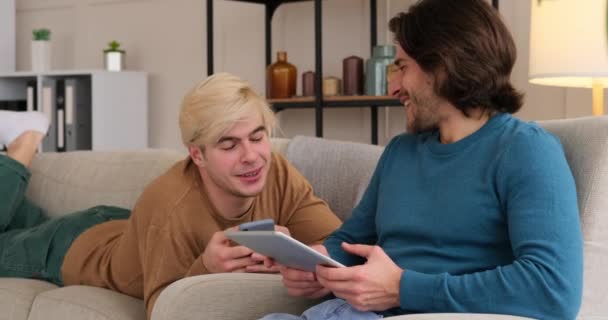 Gay couple using mobile phone and digital tablet at home — Stock Video