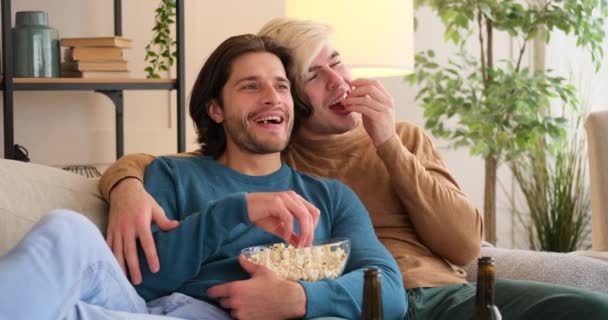 Pareja gay comiendo palomitas de maíz y viendo televisión en casa — Vídeo de stock