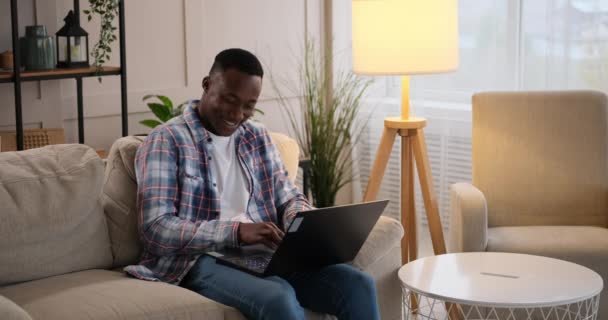 Człowiek śmieje się podczas rozmowy na laptopie w domu — Wideo stockowe