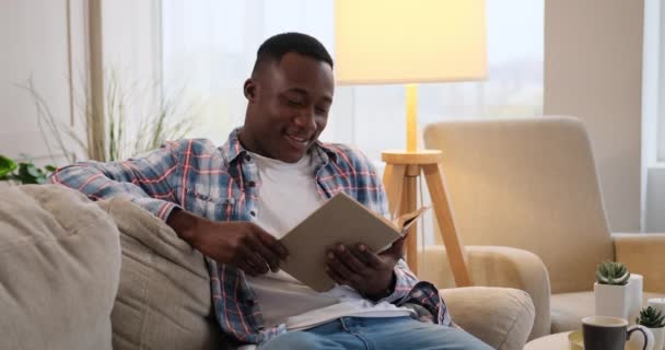 Zmatený muž čte doma knihu na pohovce — Stock video
