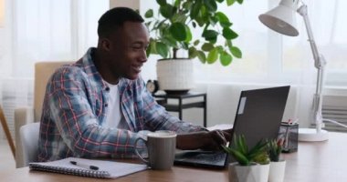 Afro-Amerikalı iş adamı laptopta çalışıyor ve kahve içiyor.