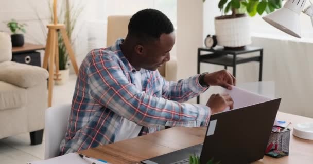 African american businessman working on laptop and analyzing document — Video Stock