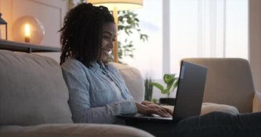 Evde dizüstü bilgisayarda yazan kadın.