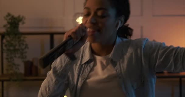 Frau singt Lied mit Fernbedienung als Mikrofon und tanzt zu Hause — Stockvideo