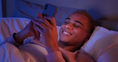 Geceleri cep telefonu kullanan mutlu bir adam.