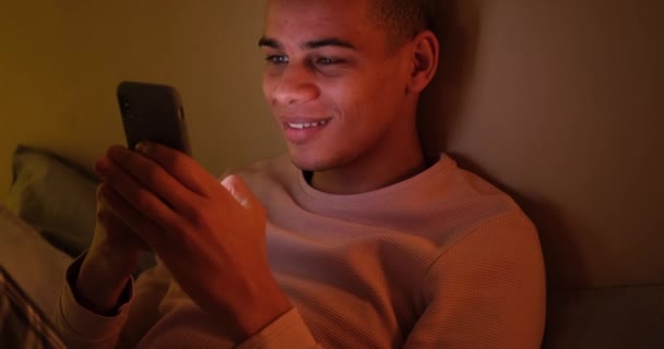 Man laughing and text messaging on mobile phone late night — Stock Video