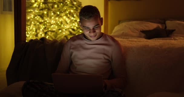 Hombre usando el ordenador portátil tarde en la noche en el dormitorio — Vídeos de Stock