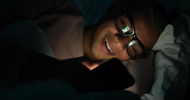 Man met bril met behulp van mobiele telefoon in bed 's nachts — Stockvideo